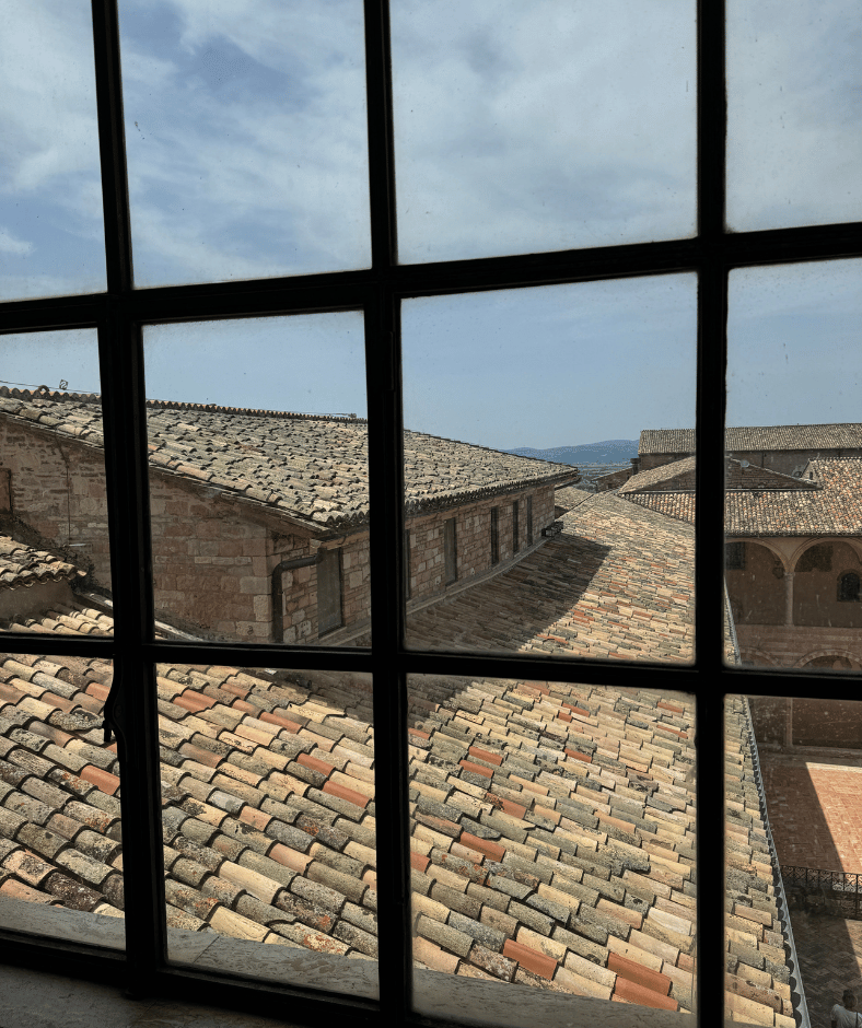 kijkje door een raam naar de binnenplaats bij de basiliek van assisi